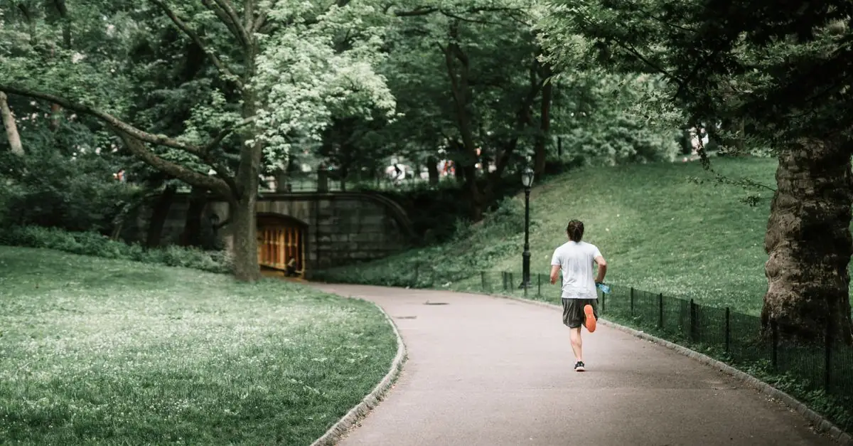 公園のベンチで休息日を過ごしランニングシューズのひもをほどく市民ランナー